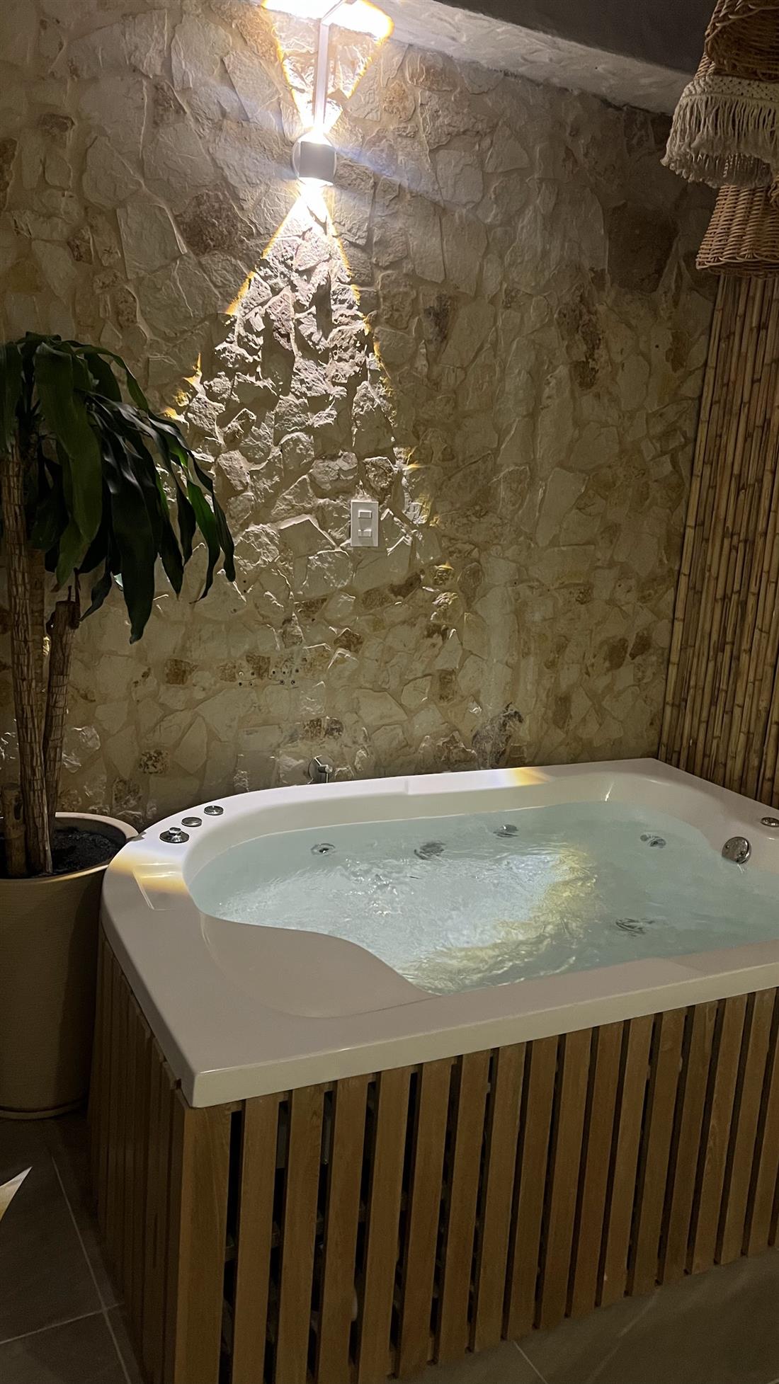 Jacuzzi frente al muro de piedra iluminado